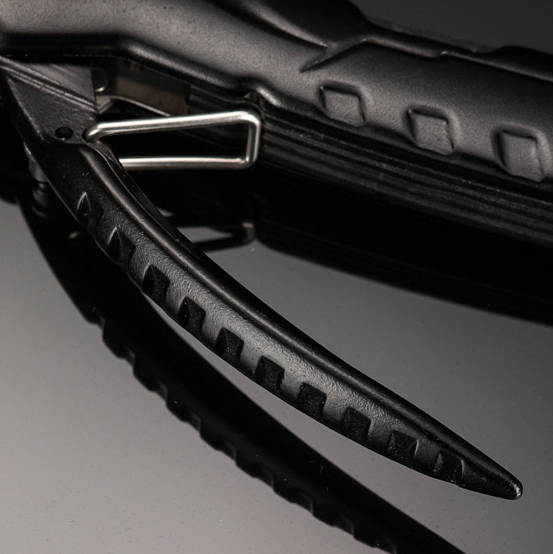 Close-up of a black multi-tool pocket knife with a textured handle and a partially extended black jaw tool, showing a silver metal pivot screw and latch.